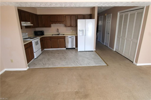 kitchen featuring light carpet, white appliances, under cabinet range hood, and a sink