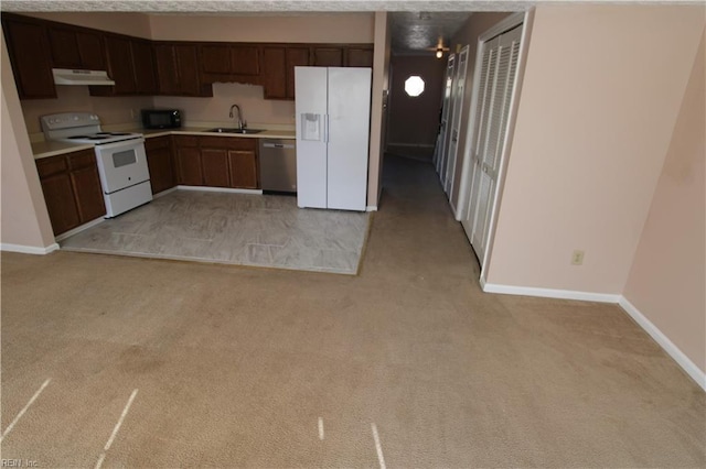 kitchen with light colored carpet, under cabinet range hood, white appliances, a sink, and light countertops