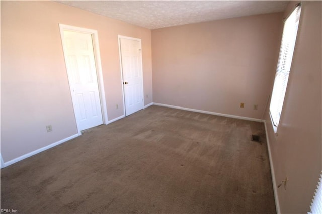 unfurnished bedroom featuring visible vents, carpet flooring, a textured ceiling, and baseboards