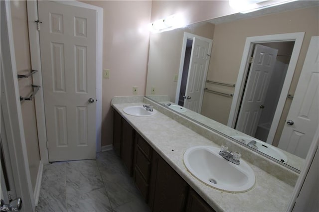 full bathroom featuring marble finish floor, a sink, and double vanity