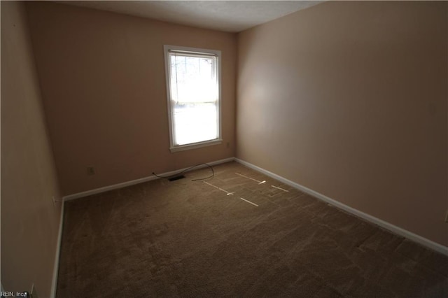 spare room with carpet flooring, visible vents, and baseboards