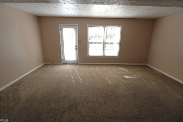 carpeted empty room with baseboards and a textured ceiling