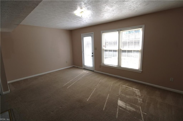 carpeted spare room featuring a textured ceiling and baseboards