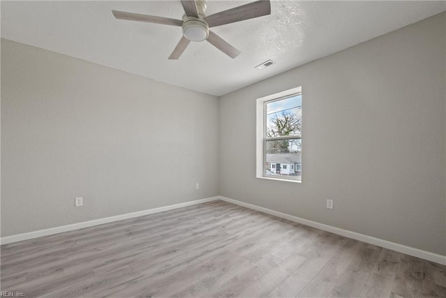 spare room featuring visible vents, a textured ceiling, wood finished floors, baseboards, and ceiling fan