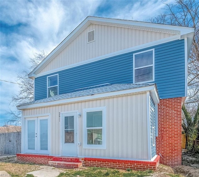 view of property exterior featuring brick siding, entry steps, roof with shingles, and fence