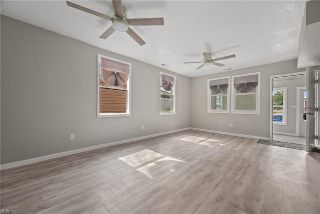 empty room featuring ceiling fan, a textured ceiling, baseboards, and wood finished floors