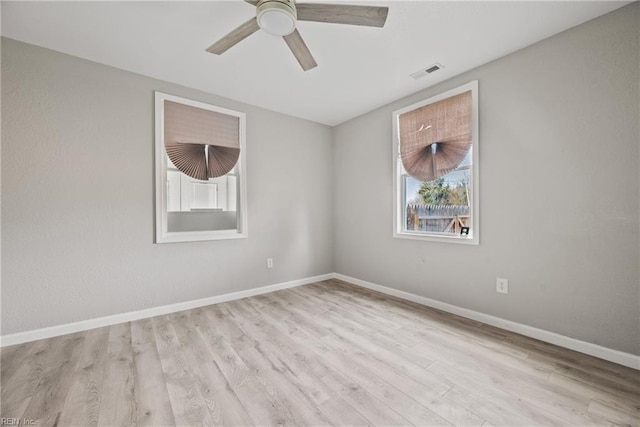 spare room with ceiling fan, visible vents, baseboards, and wood finished floors