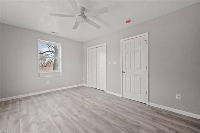 unfurnished bedroom featuring a ceiling fan, wood finished floors, visible vents, baseboards, and a closet