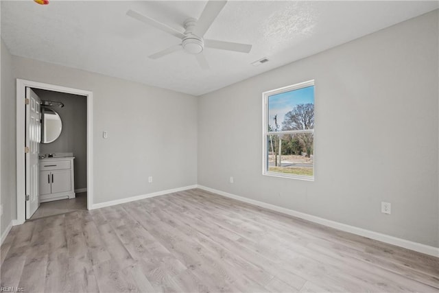 interior space featuring visible vents, baseboards, light wood-style floors, a textured ceiling, and a ceiling fan