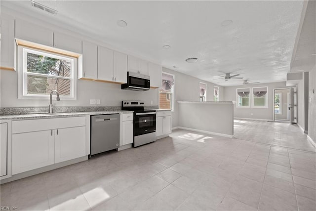 kitchen featuring visible vents, a sink, stainless steel appliances, white cabinetry, and open floor plan