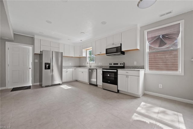 kitchen with baseboards, visible vents, a sink, stainless steel appliances, and white cabinets