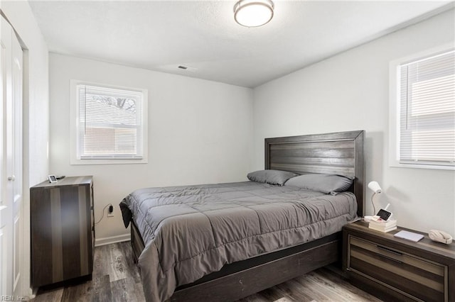 bedroom featuring baseboards, visible vents, and wood finished floors