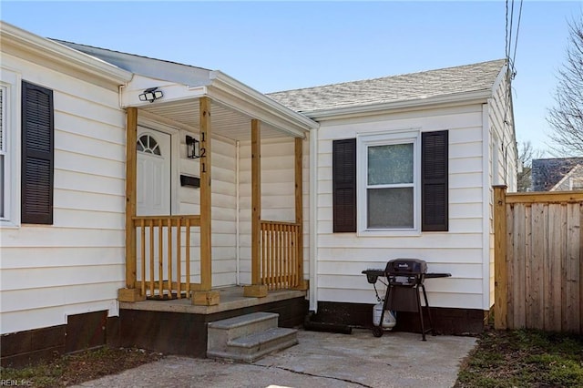 entrance to property with fence and roof with shingles