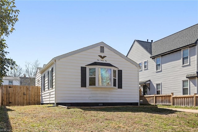 rear view of property featuring crawl space, fence, and a lawn