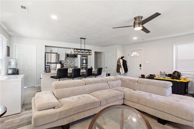 living room featuring light wood-style floors, recessed lighting, visible vents, and ceiling fan