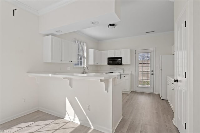 kitchen featuring light wood-style flooring, a breakfast bar, white appliances, and a peninsula