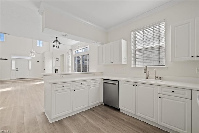 kitchen featuring crown molding, open floor plan, a sink, dishwasher, and a peninsula