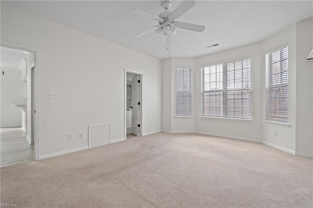 carpeted empty room featuring visible vents, ceiling fan, a textured ceiling, and baseboards