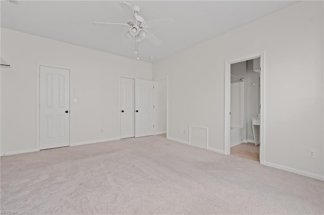 unfurnished bedroom with carpet floors, ensuite bath, two closets, and baseboards