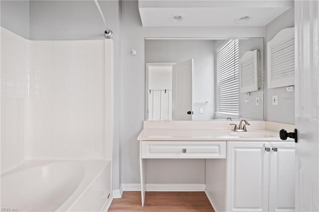 bathroom featuring  shower combination, baseboards, wood finished floors, and vanity