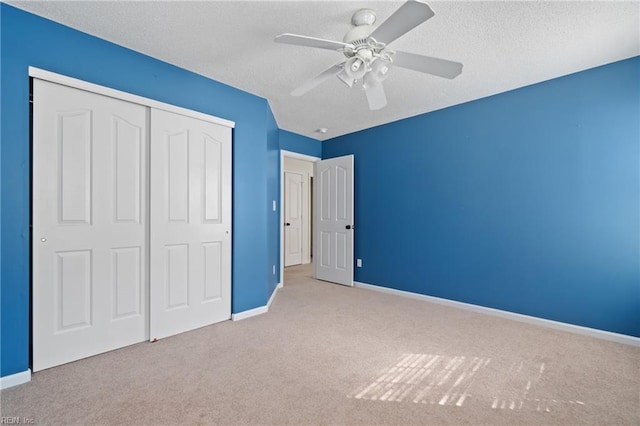 unfurnished bedroom with a textured ceiling, carpet floors, a closet, and baseboards