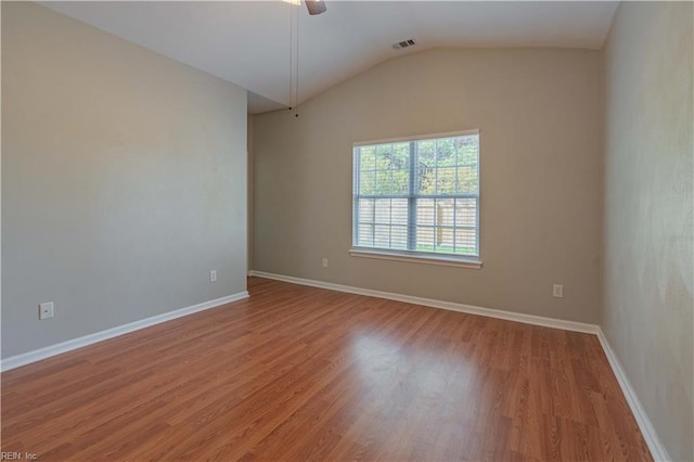 empty room featuring lofted ceiling, ceiling fan, wood finished floors, visible vents, and baseboards