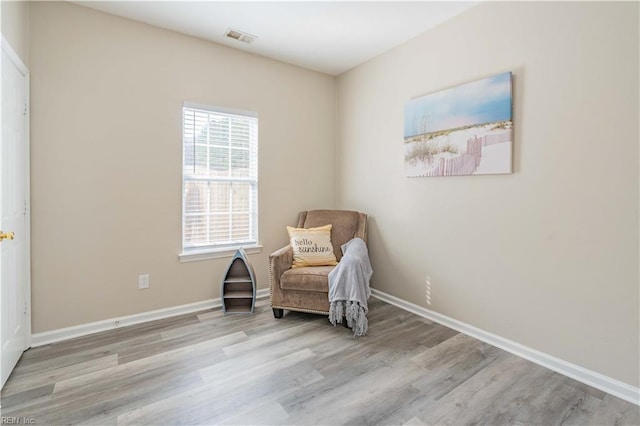 living area with baseboards, visible vents, and wood finished floors