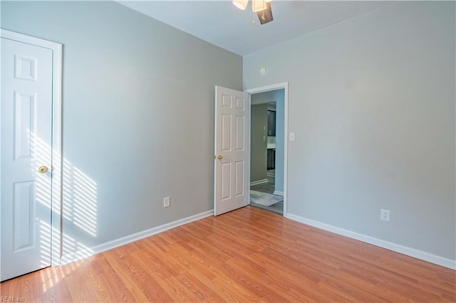 spare room with a ceiling fan, light wood-style flooring, and baseboards