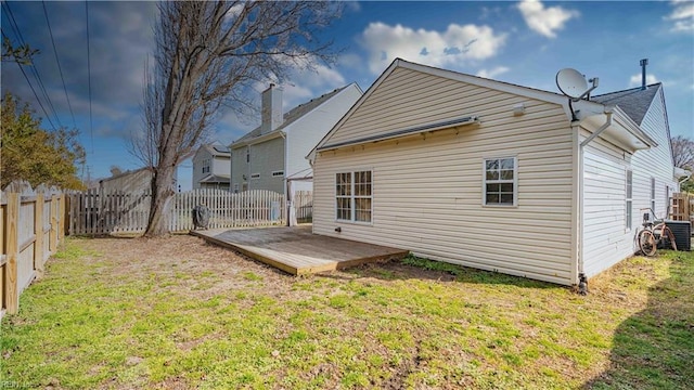 back of property with a deck, a yard, and a fenced backyard