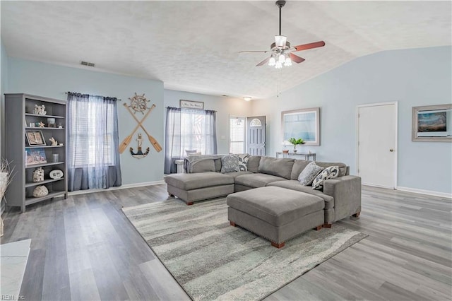 living room featuring vaulted ceiling, baseboards, and wood finished floors