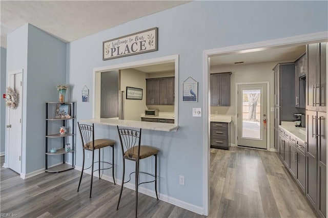 kitchen with light countertops, a breakfast bar area, and wood finished floors