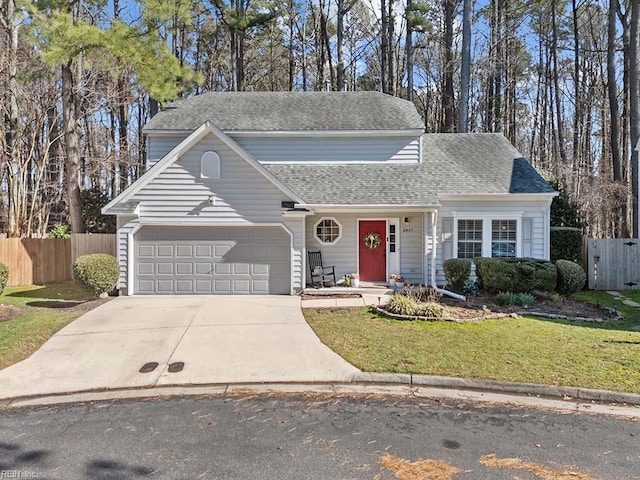 traditional-style house with concrete driveway, roof with shingles, an attached garage, fence, and a front lawn