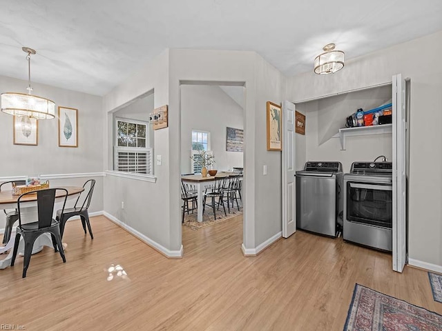 dining area featuring baseboards, washer and clothes dryer, an inviting chandelier, and light wood-style floors