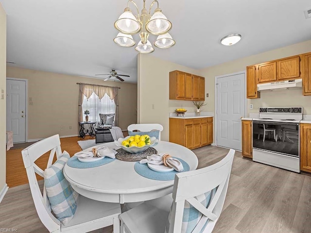 dining area with ceiling fan with notable chandelier, light wood finished floors, visible vents, and baseboards