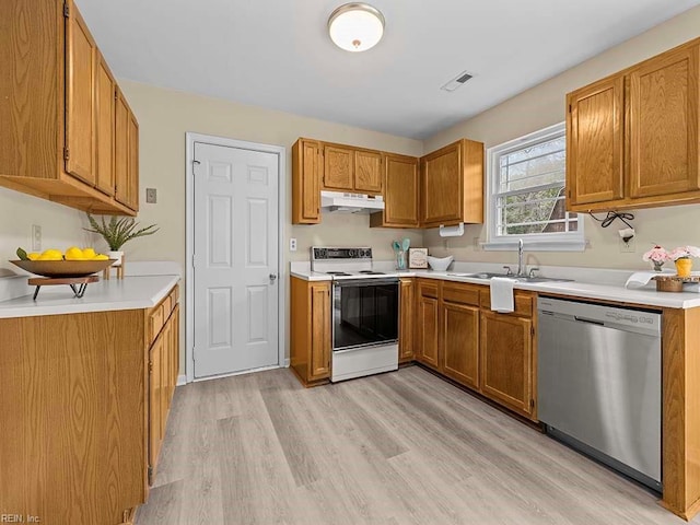 kitchen featuring electric range, dishwasher, brown cabinets, under cabinet range hood, and a sink