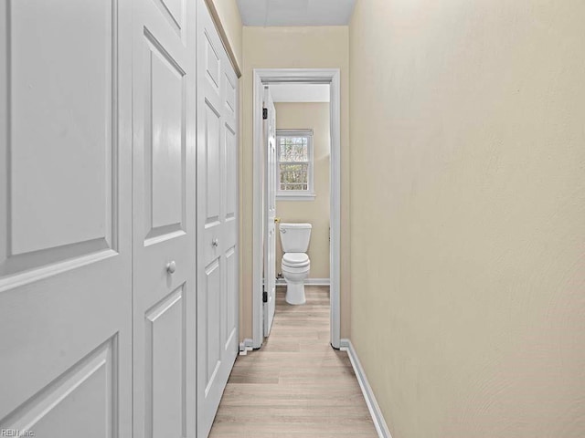 corridor featuring light wood finished floors and baseboards