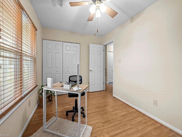 office space with light wood finished floors, a ceiling fan, and baseboards