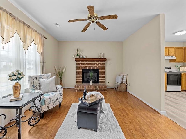 living area with visible vents, a fireplace, light wood-style flooring, and baseboards