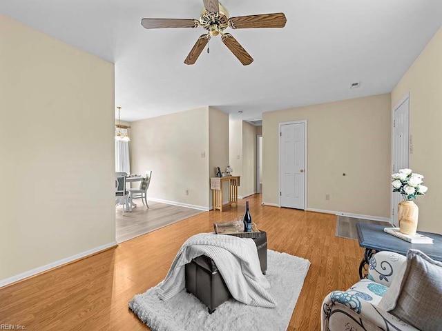 living room with light wood-style floors, visible vents, ceiling fan, and baseboards