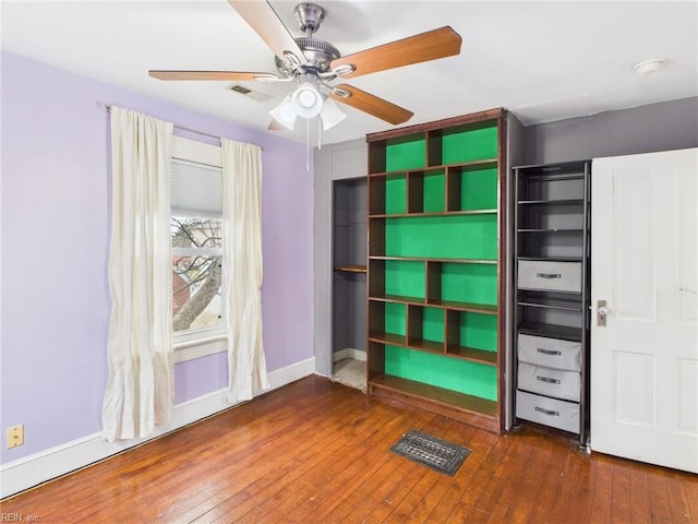 unfurnished bedroom with a ceiling fan, wood-type flooring, visible vents, and baseboards