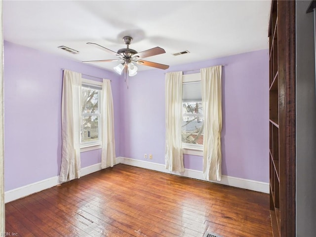 unfurnished room featuring baseboards, visible vents, ceiling fan, and hardwood / wood-style floors