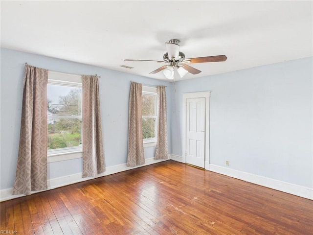 unfurnished room with hardwood / wood-style flooring, visible vents, baseboards, and a ceiling fan