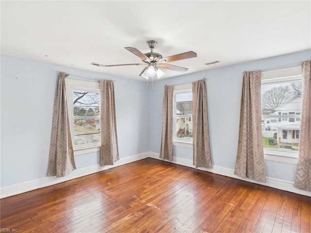 unfurnished room with a ceiling fan, visible vents, baseboards, and hardwood / wood-style floors