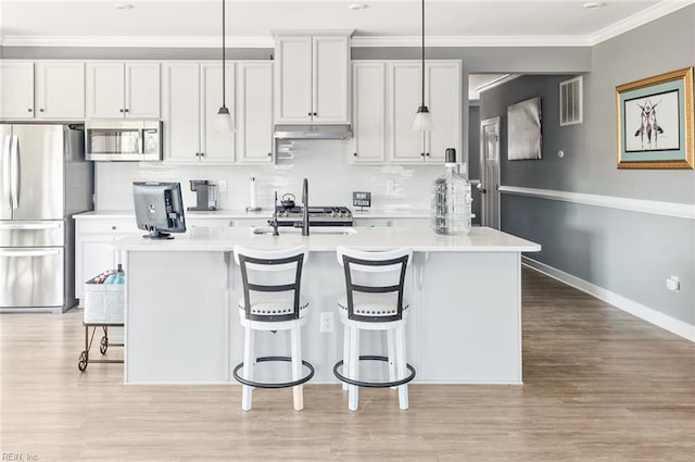 kitchen with visible vents, stainless steel appliances, light countertops, under cabinet range hood, and crown molding