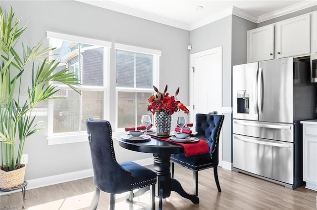 dining space with baseboards, light wood-style floors, and ornamental molding