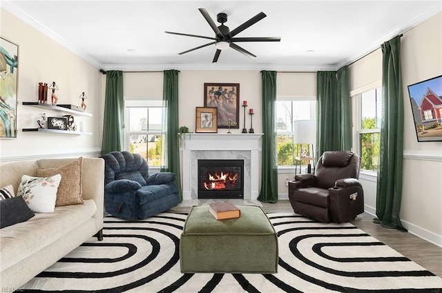 living room featuring a high end fireplace, a healthy amount of sunlight, wood finished floors, and ornamental molding