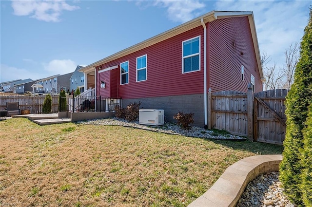 back of house with a gate, a lawn, brick siding, and fence