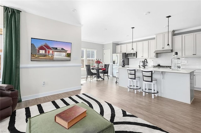 living area with baseboards, light wood finished floors, and ornamental molding