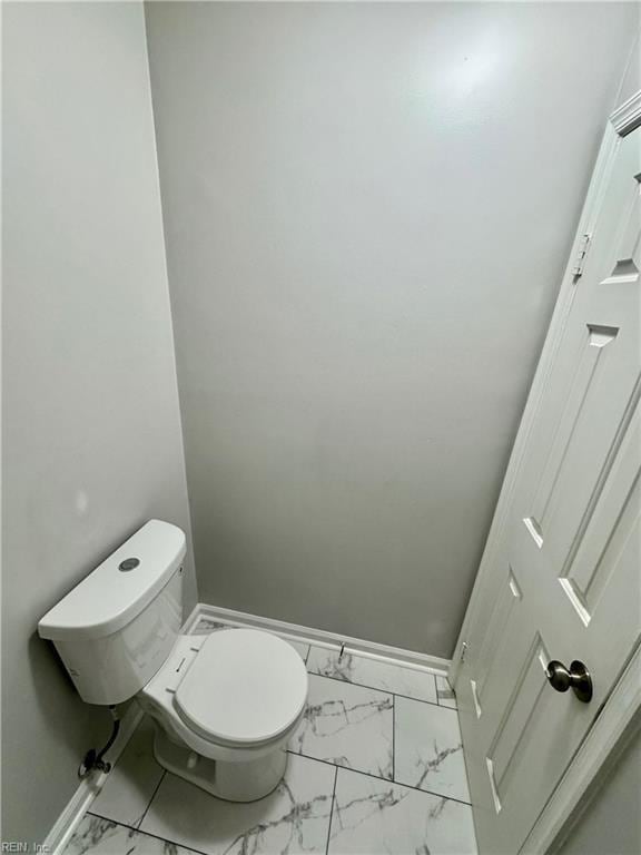 bathroom featuring toilet, marble finish floor, and baseboards