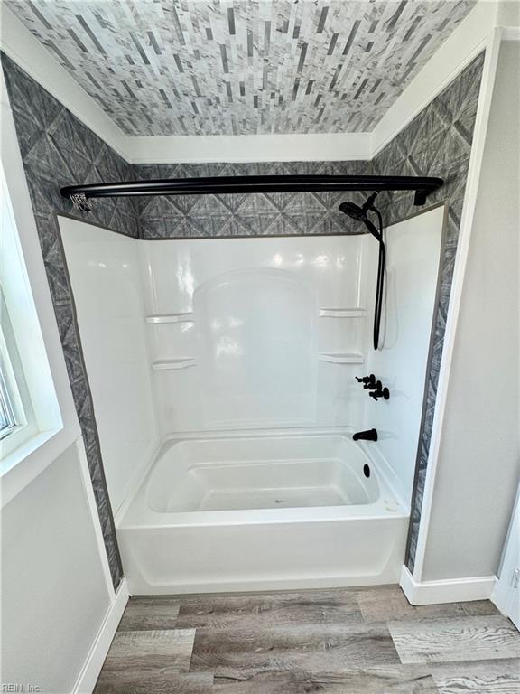 bathroom with shower / bath combination, baseboards, and wood finished floors